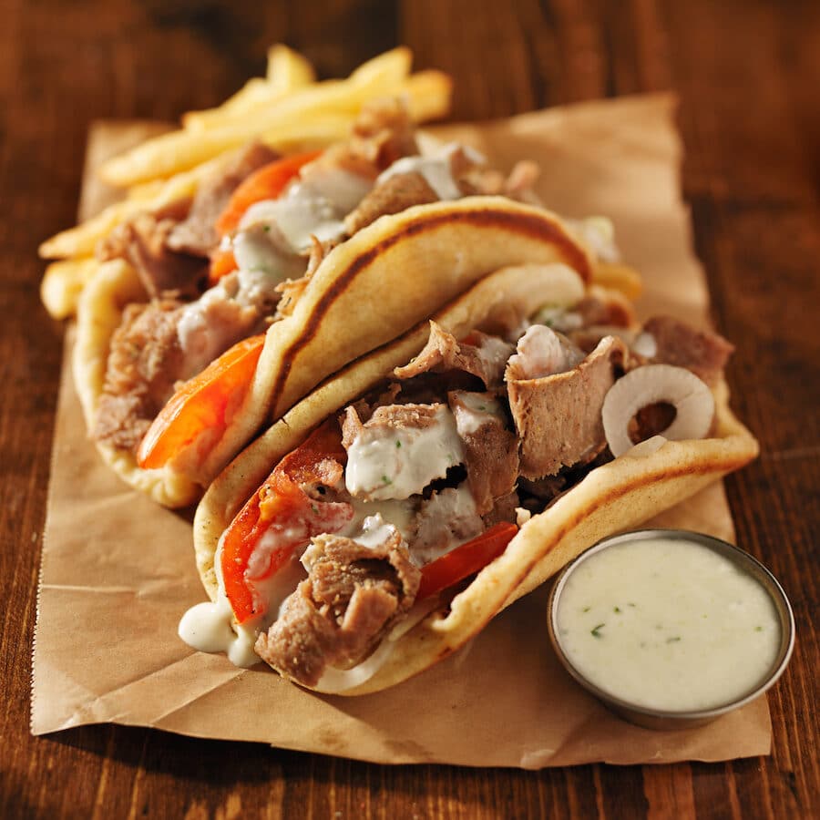 Food in Greece - greek gyros with tzatziki sauce and fries on parchment